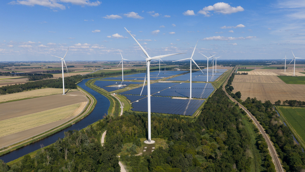Aerial view of Zonnepark Eekerpolder featuring solar panels and wind turbines situated near a canal and agricultural fields under a clear blue sky Scheemda Groningen Netherlands. Aerial view of Zonnepark Eekerpolder featuring solar panels and wind turbines situated near a canal and agricultural fields under a clear blue sky Scheemda Groningen Netherlands.