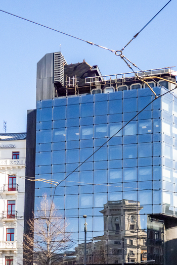 View of a modern glass fronted building reflecting a historic architectural facade under a clear blue sky in Greater Bilbao Basque Country Spain. View of a modern glass fronted building reflecting a historic architectural facade under a clear blue sky in Greater Bilbao Basque Country Spain.