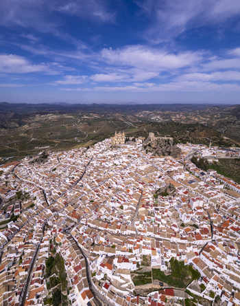 Aerial view of the historic town of Olvera with its prominent church and castle perched on a hill surrounded by white houses and rolling countryside in Olvera Andalusia Spain. Aerial view of the historic town of Olvera with its prominent church and castle perched on a hill surrounded by white houses and rolling countryside in Olvera Andalusia Spain.