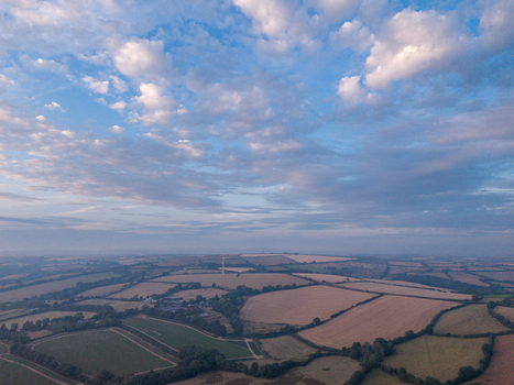 Aerial view of agricultural farmland featuring hedgerows tracks and freshly harvested fields under a blue sky in Looe Cornwall United Kingdom. Aerial view of agricultural farmland featuring hedgerows tracks and freshly harvested fields under a blue sky in Looe Cornwall United Kingdom.