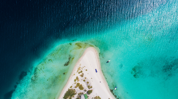 Aerial view of the white sand beach of Los Roques archipelago surrounded by turquoise Caribbean sea with small boats anchored nearby in Los Roques Dependencias Federale Venezuela. Aerial view of the white sand beach of Los Roques archipelago surrounded by turquoise Caribbean sea with small boats anchored nearby in Los Roques Dependencias Federale Venezuela.