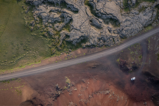 Aerial view of Ytri Raudarmelskula volcanic crater with rugged lava fields a winding road and a car parked nearby in Raudhamelur Eyja og Miklaholtshr Iceland. Aerial view of Ytri Raudarmelskula volcanic crater with rugged lava fields a winding road and a car parked nearby in Raudhamelur Eyja og Miklaholtshr Iceland.