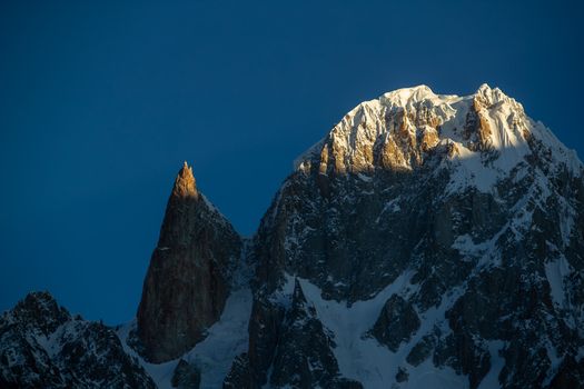 View of Lady Finger peak and snow capped mountains illuminated by golden hour light against a clear blue sky in Hunza Nagar Gilgit Pakistan. View of Lady Finger peak and snow capped mountains illuminated by golden hour light against a clear blue sky in Hunza Nagar Gilgit Pakistan.