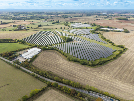 Aerial view of Chesterton Solar Farm featuring rows of photovoltaic panels set within rural agricultural fields surrounded by green hedges and trees in Warwickshire United Kingdom. Aerial view of Chesterton Solar Farm featuring rows of photovoltaic panels set within rural agricultural fields surrounded by green hedges and trees in Warwickshire United Kingdom.