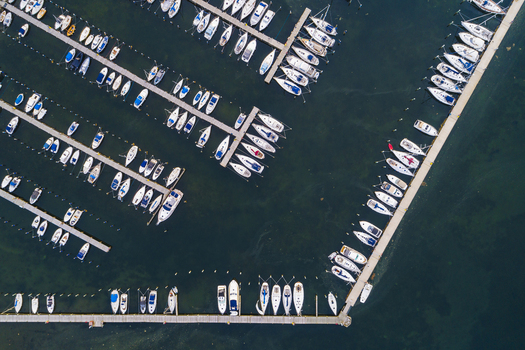 Aerial view of Sando marina featuring numerous sailboats and motorboats docked in organized rows within the calm waters of the harbor in Vallda Hallands lan Sweden. Aerial view of Sando marina featuring numerous sailboats and motorboats docked in organized rows within the calm waters of the harbor in Vallda Hallands lan Sweden.