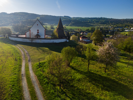 Aerial view of the historic Church of St. Martin with its wooden bell tower and fortified wall on a green hill in Cerin Banskobystricky kraj Slovakia. Aerial view of the historic Church of St. Martin with its wooden bell tower and fortified wall on a green hill in Cerin Banskobystricky kraj Slovakia.