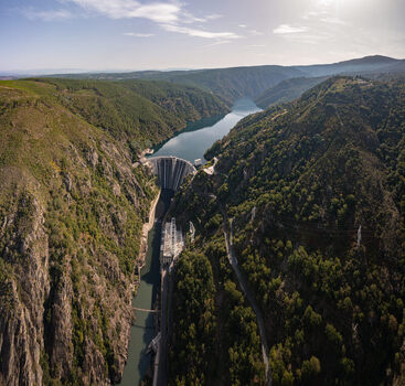 Aerial view of Encoro de Santo Estevo dam situated in a deep river canyon surrounded by lush green hills and rocky cliffs under a clear sky Ourense Ourense Spain. Aerial view of Encoro de Santo Estevo dam situated in a deep river canyon surrounded by lush green hills and rocky cliffs under a clear sky Ourense Ourense Spain.