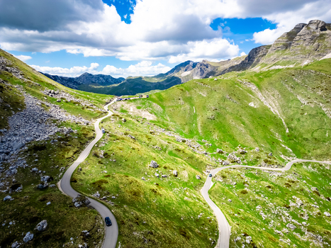 Aerial view of the winding road through the mountainous landscape near Bobotov Kuk with green slopes and rocky terrain in Zabljak Municipality Montenegro. Aerial view of the winding road through the mountainous landscape near Bobotov Kuk with green slopes and rocky terrain in Zabljak Municipality Montenegro.
