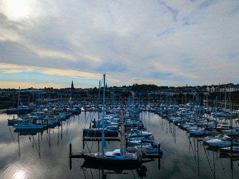Aerial view of Bangor Harbour and Town filled with sailboats and yachts moored in calm water with the town skyline under a cloudy sky in Bangor Northern Ireland United Kingdom.