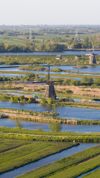 Aerial view of historic windmills standing along the canals and lush green polders under soft daylight Kinderdijk South Holland Netherlands. Aerial view of historic windmills standing along the canals and lush green polders under soft daylight Kinderdijk South Holland Netherlands.
