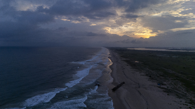 Aerial view of Tarkwa Bay Beach at sunset with waves crashing onto the sandy shore under a dramatic cloudy sky in Lagos Lagos Nigeria. Aerial view of Tarkwa Bay Beach at sunset with waves crashing onto the sandy shore under a dramatic cloudy sky in Lagos Lagos Nigeria.