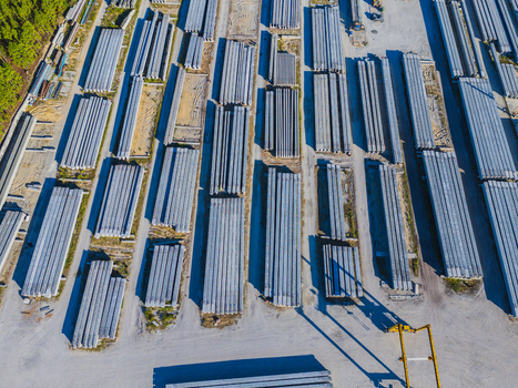 Aerial view of an industrial concrete bridge manufacturing facility with rows of steel I beams heavy machinery and storage yards in Wilmington North Carolina United States. Aerial view of an industrial concrete bridge manufacturing facility with rows of steel I beams heavy machinery and storage yards in Wilmington North Carolina United States.