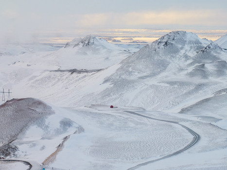 Aerial view of the snowy volcanic landscape near Myvatn with a small red building and a winding road in Thingeyjarsveit Iceland. Aerial view of the snowy volcanic landscape near Myvatn with a small red building and a winding road in Thingeyjarsveit Iceland.