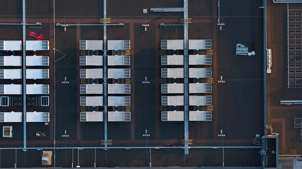Aerial view of a flat industrial building roof featuring rows of HVAC units and solar panels arranged in a grid pattern in Bracknell England United Kingdom.
