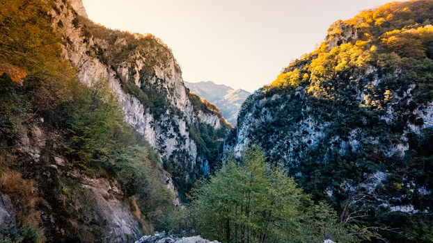 View of Gola dell Infernaccio gorge with steep limestone cliffs and autumn colored trees under a clear sky Montefortino Marche Italy. View of Gola dell Infernaccio gorge with steep limestone cliffs and autumn colored trees under a clear sky Montefortino Marche Italy.