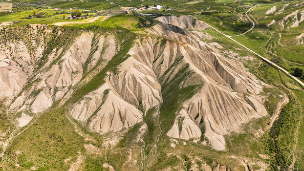 Aerial view of sun drenched barren hills contrast with patches of vibrant green vegetation creating a textured landscape of earthy tones Centuripe Sicilia Italy. Aerial view of sun drenched barren hills contrast with patches of vibrant green vegetation creating a textured landscape of earthy tones Centuripe Sicilia Italy.