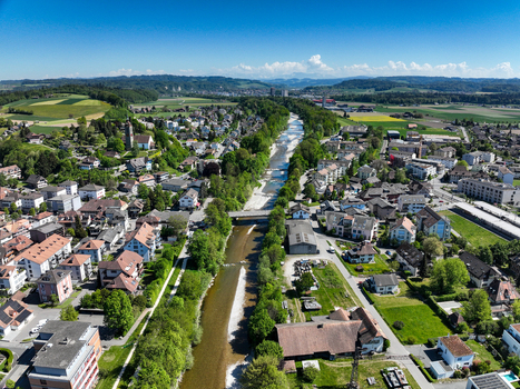 Aerial view of the Emmensteg bridge crossing the Emme river surrounded by residential houses and lush green trees in Kirchberg Bern Switzerland. Aerial view of the Emmensteg bridge crossing the Emme river surrounded by residential houses and lush green trees in Kirchberg Bern Switzerland.