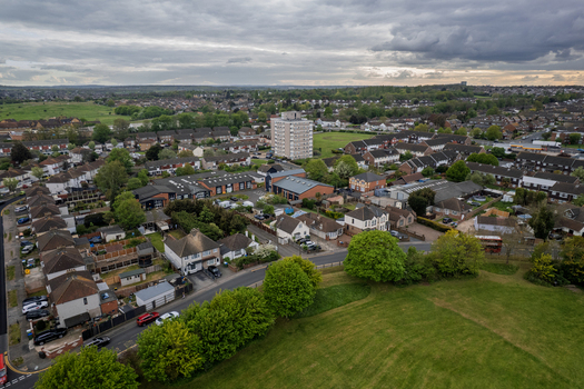 Aerial view of houses nestled amidst lush greenery with a tall apartment building standing out against the cloudy sky Slade green United Kingdom.