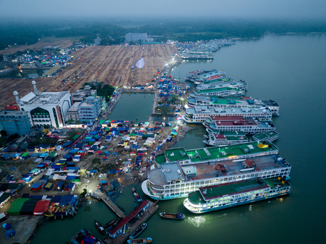Aerial view of a bustling waterfront with gleaming white boats docked along the shore contrasting with the colorful tents and buildings Charmonai Barisal Division Bangladesh. Aerial view of a bustling waterfront with gleaming white boats docked along the shore contrasting with the colorful tents and buildings Charmonai Barisal Division Bangladesh.