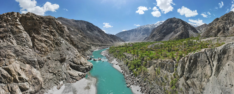 Aerial view of Gol Valley with a turquoise river flowing through rocky cliffs and lush green vegetation in Skardu Gilgit Baltistan Pakistan.