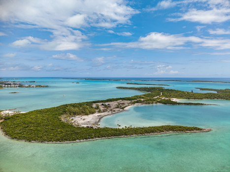 Aerial view of Crab Cay featuring lush green vegetation and white sand beaches surrounded by turquoise tropical waters under a blue sky in Exuma Exuma The Bahamas. Aerial view of Crab Cay featuring lush green vegetation and white sand beaches surrounded by turquoise tropical waters under a blue sky in Exuma Exuma The Bahamas.