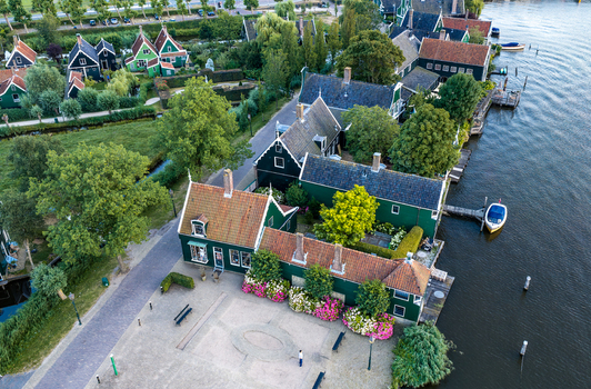 Aerial view of the historic Zaanse Schans area featuring traditional green wooden houses lush gardens and a canal in Zaandam Noord Holland Netherlands.