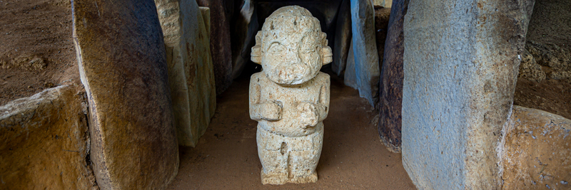 View of a pre Columbian stone statue standing inside a historic burial chamber at San Agustin Archaeological Park in San Agustin Huila Colombia.