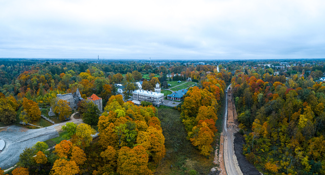 Aerial view of the historic Sigulda Castle ruins surrounded by vibrant autumn foliage lush trees and nearby buildings in Sigulda Sigulda Municipality Latvia. Aerial view of the historic Sigulda Castle ruins surrounded by vibrant autumn foliage lush trees and nearby buildings in Sigulda Sigulda Municipality Latvia.