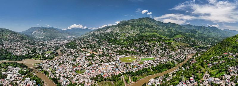 Aerial view of the city of Muzaffarabad nestled in the mountains of Azad Kashmir featuring the cricket stadium winding rivers and dense urban housing in Muzaffarabad Azad Kashmir Pakistan. Aerial view of the city of Muzaffarabad nestled in the mountains of Azad Kashmir featuring the cricket stadium winding rivers and dense urban housing in Muzaffarabad Azad Kashmir Pakistan.