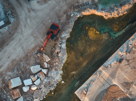 Aerial view of the Jadrankamen stone quarry featuring a red excavator large white blocks and a pool of water in Pucisca Splitsko dalmatinska Croatia. Aerial view of the Jadrankamen stone quarry featuring a red excavator large white blocks and a pool of water in Pucisca Splitsko dalmatinska Croatia.