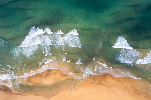 Aerial view of Raudisandur beach with golden sand and turquoise waves crashing on the shore in Vesturbyggd Iceland. Aerial view of Raudisandur beach with golden sand and turquoise waves crashing on the shore in Vesturbyggd Iceland.