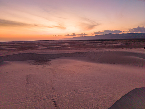 Aerial view of the desert landscape where the dunes meet the horizon under a soft gradient sky Hamlah Yemen.