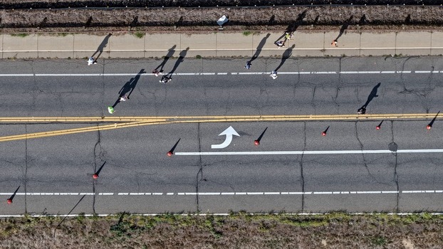 Aerial view of people walking along a road marked with a white turn arrow and traffic cones in Boulder Colorado United States. Aerial view of people walking along a road marked with a white turn arrow and traffic cones in Boulder Colorado United States.
