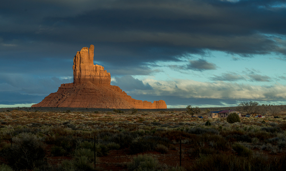 View of the iconic red rock formations at Monument Valley Tribal Park under dramatic storm clouds during golden hour in Oljato Monument Valley Utah United States.