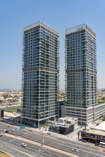 Aerial view of the modern twin skyscrapers with glass facades overlooking a busy multi lane highway and the urban skyline under a clear blue sky in Dubai Dubai United Arab Emirates. Aerial view of the modern twin skyscrapers with glass facades overlooking a busy multi lane highway and the urban skyline under a clear blue sky in Dubai Dubai United Arab Emirates.