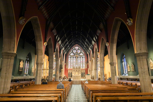 View of the interior of St Mary s Cathedral featuring wooden pews stone arches and a large stained glass window in Newcastle upon Tyne England United Kingdom. View of the interior of St Mary s Cathedral featuring wooden pews stone arches and a large stained glass window in Newcastle upon Tyne England United Kingdom.