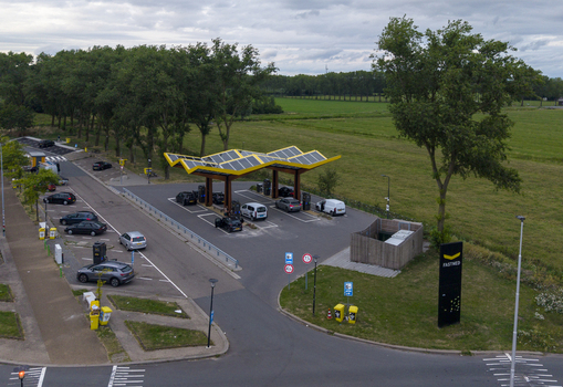 Aerial view of Fastned Charging Station with solar panel roof parked electric vehicles and surrounding green landscape in Beesd Gelderland Netherlands. Aerial view of Fastned Charging Station with solar panel roof parked electric vehicles and surrounding green landscape in Beesd Gelderland Netherlands.