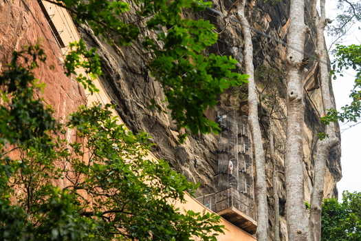 View of the metal spiral staircase on the steep rock face of Sigiriya Rock surrounded by lush green trees in Sigiriya Central Province Sri Lanka. View of the metal spiral staircase on the steep rock face of Sigiriya Rock surrounded by lush green trees in Sigiriya Central Province Sri Lanka.