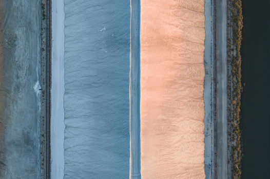 Aerial view of giant white salt mounds in the Camargue salt marshes featuring geometric patterns created by warm evening light and cool blue shadows France.