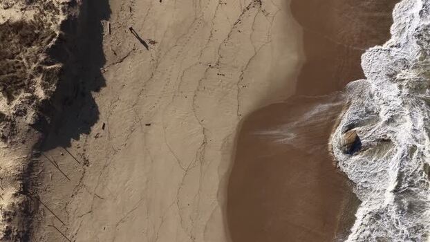 Aerial view of hiker walking on the beach with waves Portugal.
