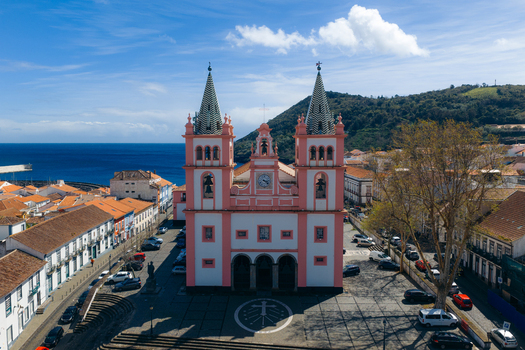 Aerial view of the historic Se Catedral de Angra do Heroismo with its pink facade and twin towers overlooking the city rooftops and the blue ocean Angra do Heroismo Azores Portugal.