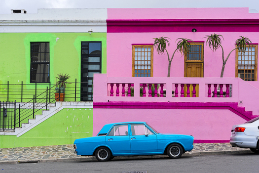 View of colorful pink and green houses with a blue vintage car parked on a cobblestone street in Bo Kaap Cape Town Western Cape South Africa. View of colorful pink and green houses with a blue vintage car parked on a cobblestone street in Bo Kaap Cape Town Western Cape South Africa.