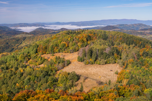 Aerial view of Sitno mountain landscape in autumn with colorful forests dry grassland and distant rolling hills under a clear blue sky in Ilija Banska Bystrica Region Slovakia. Aerial view of Sitno mountain landscape in autumn with colorful forests dry grassland and distant rolling hills under a clear blue sky in Ilija Banska Bystrica Region Slovakia.