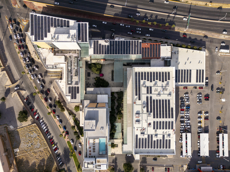 Aerial view of a modern building complex featuring extensive rooftop solar panel arrays a parking lot with numerous vehicles and a swimming pool in Chihuahua Chihuahua Mexico. Aerial view of a modern building complex featuring extensive rooftop solar panel arrays a parking lot with numerous vehicles and a swimming pool in Chihuahua Chihuahua Mexico.