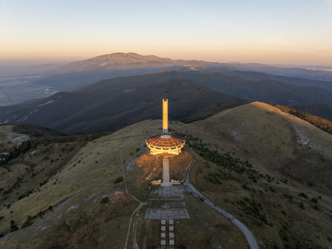 Aerial view of the Buzludzha Monument on a mountain peak at sunset with surrounding hills and landscape in Stara Zagora Bulgaria. Aerial view of the Buzludzha Monument on a mountain peak at sunset with surrounding hills and landscape in Stara Zagora Bulgaria.
