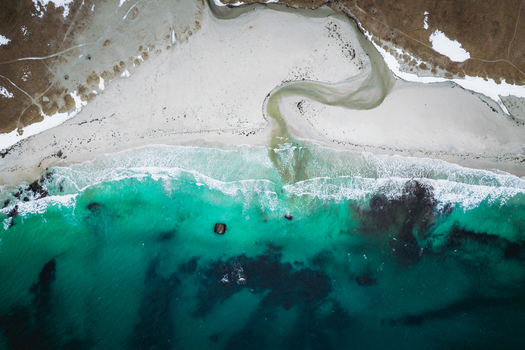 Aerial view of the mesmerizing turquoise sea meeting the white sandy beach at Uttakleivveien creating a stunning contrast against the rugged landscape Haukland Beach Nordland Norway. Aerial view of the mesmerizing turquoise sea meeting the white sandy beach at Uttakleivveien creating a stunning contrast against the rugged landscape Haukland Beach Nordland Norway.