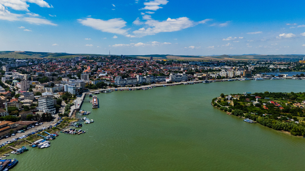 Aerial view of the city of Tulcea situated along the Danube River with boats docked at the waterfront urban buildings and green hills in Tulcea Tulcea Romania. Aerial view of the city of Tulcea situated along the Danube River with boats docked at the waterfront urban buildings and green hills in Tulcea Tulcea Romania.