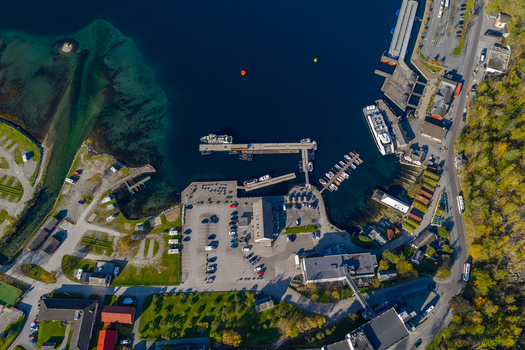 Aerial view of the harbor in Geiranger with boats docked at the pier a parking lot and surrounding buildings in Geiranger More og Romsdal Norway. Aerial view of the harbor in Geiranger with boats docked at the pier a parking lot and surrounding buildings in Geiranger More og Romsdal Norway.