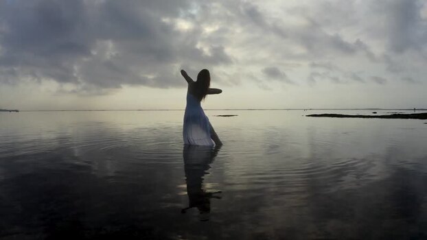 Aerial view of a woman in a white dress standing in the ocean Indonesia.