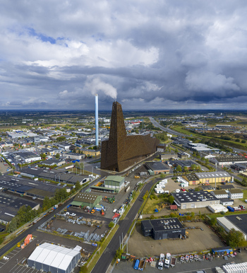 Aerial view of the Energitarnet waste to energy plant with its iconic perforated facade and smoking chimney in an industrial district under a cloudy sky Roskilde Denmark. Aerial view of the Energitarnet waste to energy plant with its iconic perforated facade and smoking chimney in an industrial district under a cloudy sky Roskilde Denmark.